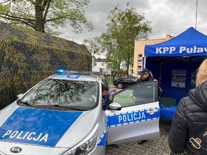 ojciec z dzieckiem za kierownicą radiowozu obok policjantka