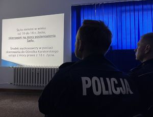 policjanci patrzący na ekran z wyświetlonym tekstem