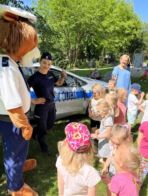 policjantka z dziećmi i policyjną maskotką