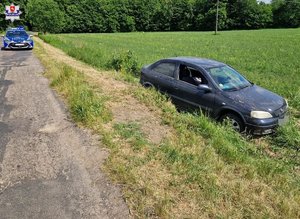 granatowy opel w rowie w tle radiowóz policji