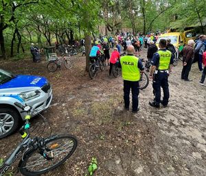 policjanci patrzący na grupę uczestników rajdu którzy dojechali na polanę w lesie