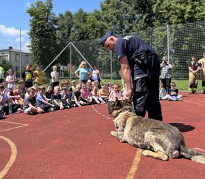policjant z warującym psem przed dziećmi