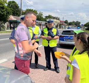 mężczyzna stojący obok policjantów dzieci podają mu cytryny w miseczce