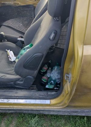 wnętrze samochodu osobowego za fotelem kierowcy butelki po piwie