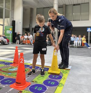 policjantka pomagająca chłopcu ustawić pachołek na planszy
