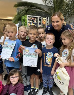 policjantka z dziećmi prezentującymi dyplom