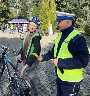policjant zakładający opaskę odblaskową nastolatkowi na rowerze
