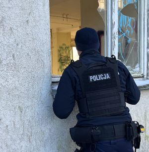 policjant zaglądający przez wybite okno