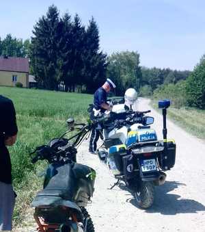policjant przy motocyklu obok kierowca z drugim motocyklem