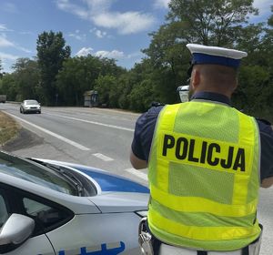 policjant przy drodze mierzący prędkość pojazdu