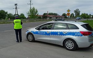 policjant mierzący prędkość nadjeżdżającego samochodu obok niego radiowóz