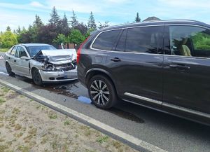 srebrny opel z rozbitym przodem stojący za czarnym volvo