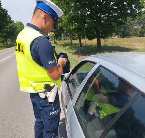 policjant z miernikiem obok samochodu w trakcie kontroli