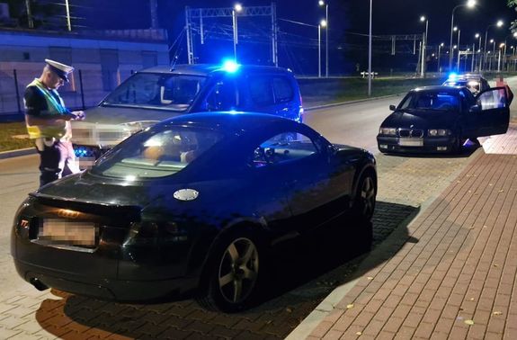 policjanci kontrolujący nocą dwa samochody audi i BMW