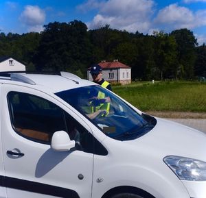 policjant badający na trzeźwość kierowcę białego samochodu