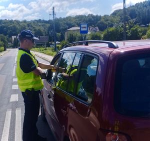 policjant przy bordowym samochodzie