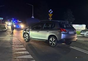 szary peugeot na szosie w tle radiowóz na sygnale i policjant kierujący ruchem