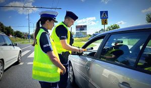 policjantka i policjant rozmawiający z kierowcą siedzącym w samochodzie