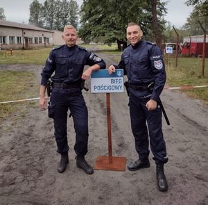 dwóch policjantów przy tabliczce bieg pościgowy