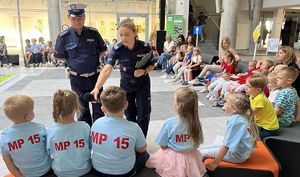 policjantka podająca mikrofon dziecku obok niej policjant