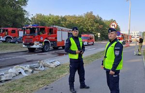 dwóch policjantów w tle wozy straży pożarnej