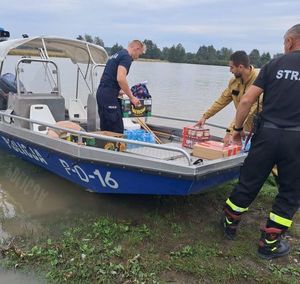 policjant układający artykuły żywnościowe na łódce