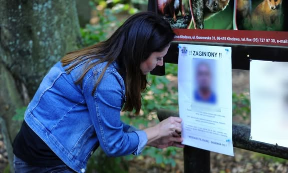 Kobieta przypinająca ogłoszenie o zaginięciu osoby