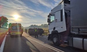 miejsce wypadku rozbity samochód na lewym boku obok ciężarówka i karetka oraz policjantka