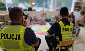 dwóch policjantów na krzesłach siedzący przed grupą dzieci w kręgu