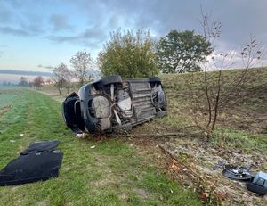 samochód leżący na boku na dole wału obok ulicy