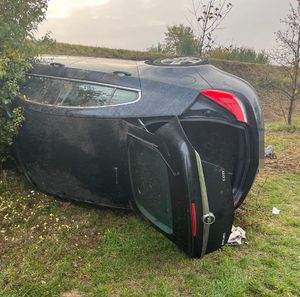 czarny opel leżący na boku w rowie