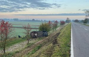 droga na Dęblin po lewej stronie na dole wału leży na boku czarny opel