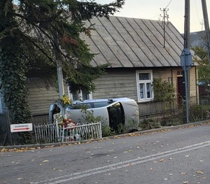 srebrny volkswagen leżący na boku na poboczu obok drewnianego domu