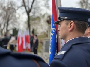 policjant z pocztu sztandarowego w tle flagi biało-czerwone