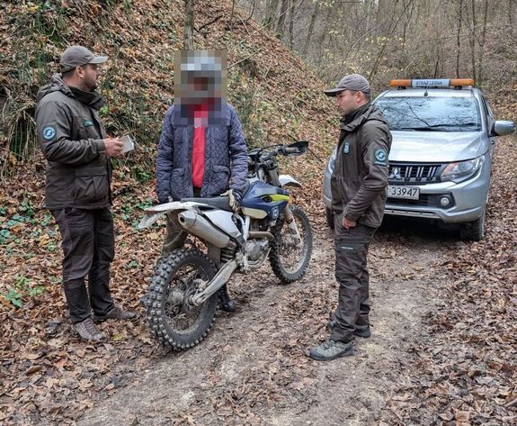 leśnicy rozmawiający z mężczyzną na motocyklu crossowym w tle samochód straży leśnej