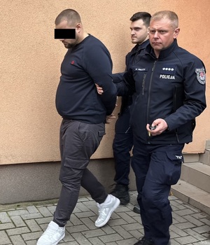 policjanci prowadzący mężczyznę w kajdankach