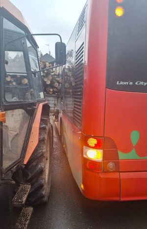 czerwony autobus obok ciągnik z gałęziami na przyczepie