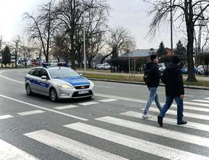 dwóch pieszych na przejściu przed nim oczekuje radiowóz