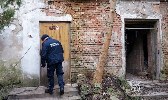 policjant obok opuszczonego budynku