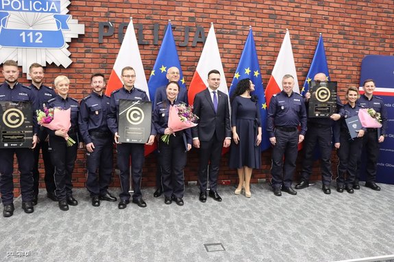 wyróżnieni policjanci z nagrodami i kwiatami