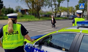 policjanci obserwujący przejście dla pieszych po którym przechodzi kobieta