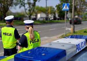 policjanci obok radiowozu przy ulicy