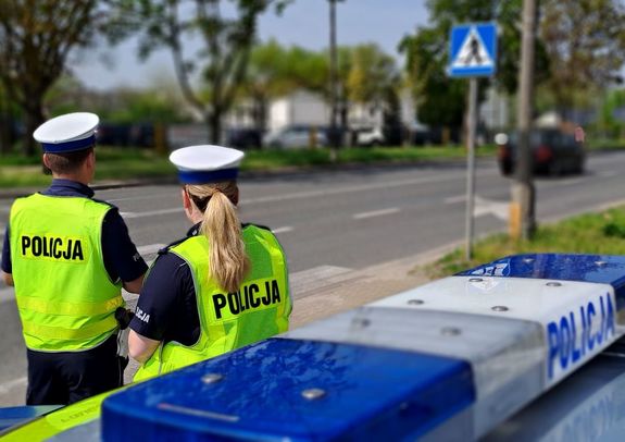 policjanci obok radiowozu przy ulicy