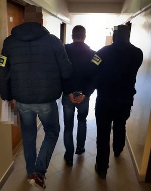 dwóch policjantów prowadzi zatrzymanego