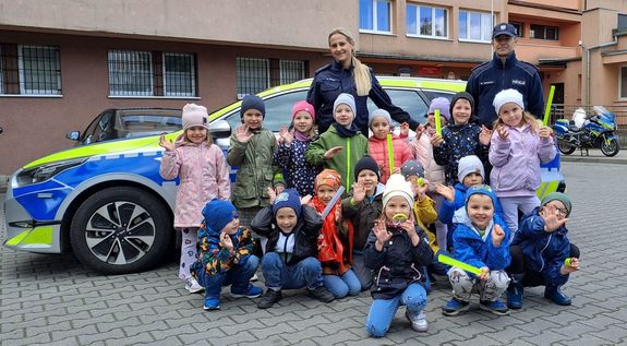 dwoje policjantów z grupą dzieci przed komendą