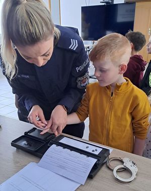 policjantka pokazująca dziecku w jaki sposób robi sie daktyloskopię