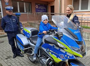 chłopiec na motocyklu obok dwoje policjantów