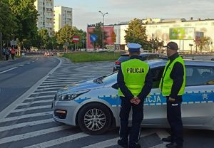 policjanci obok radiowozu obserwujący rajd