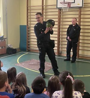 policjant prezentujący dzieciom arbuza w kasku