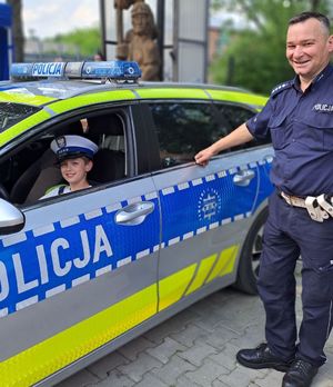 policjant obok radiowozu za kierownicą chłopiec